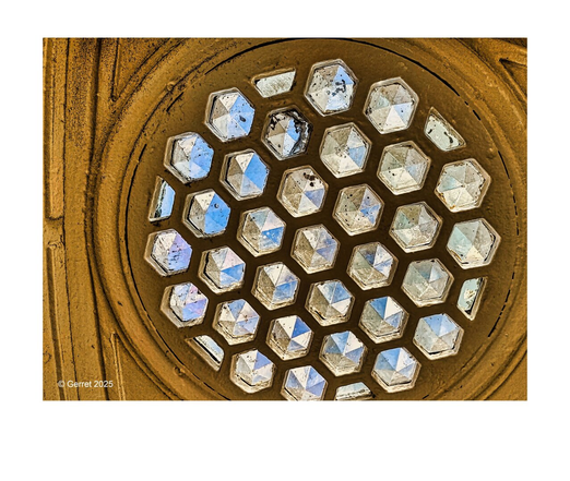 Round stained-glass skylight with hexagonal panes casting colorful reflections. The earthy brown metal frame gives a rustic contrast. Bright and intricate.