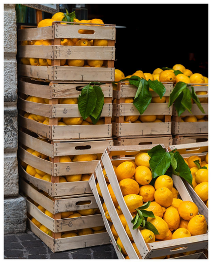 Ein paar Holzkisten mit Zitronen und Zitronenblättern stehen dekorativ vor einem Laden der - oh Wunder - Produkte aus Zitronen verhökert.