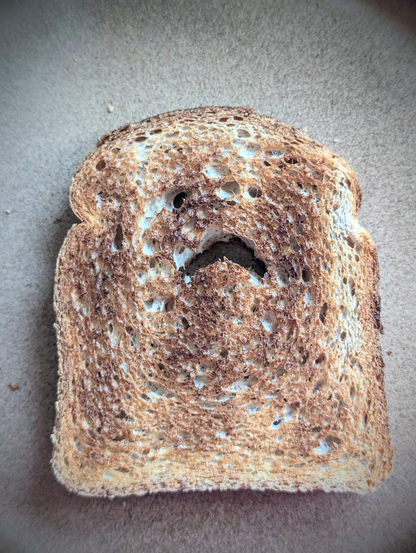 Foto einer Scheibe getoastetes Toastbrot, das Löcher hat, die wie ein erschrecktes Gesicht aussehen, Foto von Karen Kaspar