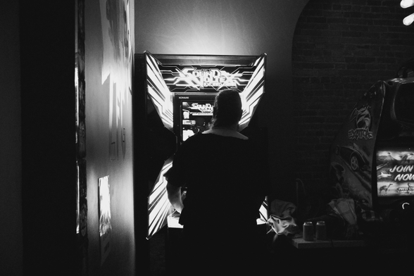 A trans person plays an arcade machine. 