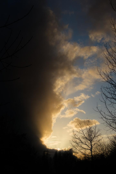 Photo d'un ciel avec sur la moitié gauche un gros nuage noir et sur la moitié droite un ciel bleu avec quelques nuages éclairés par le soleil