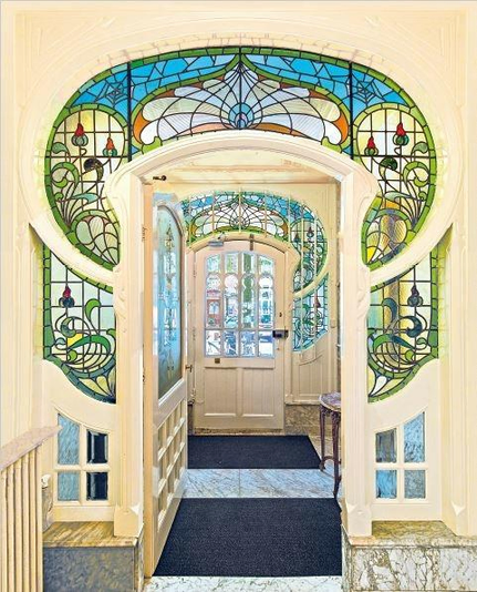 The image shows an interior doorway featuring stained glass in the Art Nouveau style. This style is characterized by its use of organic, flowing lines and natural motifs, which are evident in this