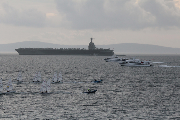 Small boats passing by the American carrier.