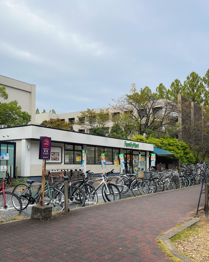 Un pequeño edificio bajo (de una planta). Es un FamilyMart (tienda de conveniencia) que se encuentra dentro del campus (no es el único). En la puerta está lleno de bicis aparcadas (de los estudiantes, muy probablemente).