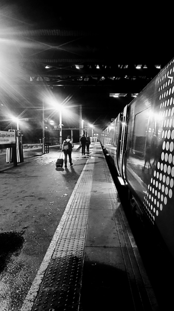Looking along the length of a train and platform at night