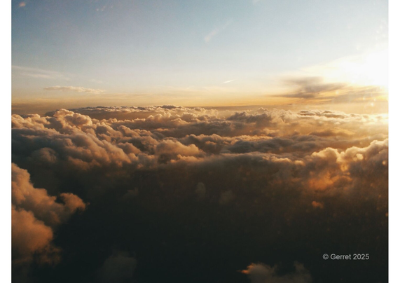 Sunset over fluffy clouds viewed from an airplane, with warm orange and yellow hues. A serene and dreamy atmosphere fills the expansive sky.