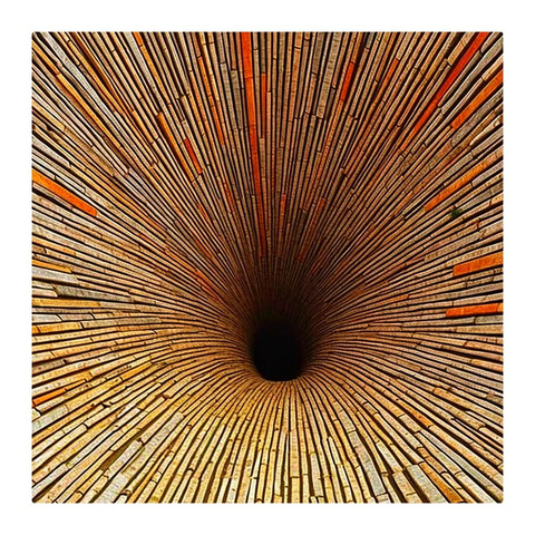 The image depicts a tunnel-like vortex, composed of numerous narrow, radiating lines converging towards a central black point. These lines, resembling planks of wood or slats, exhibit varying shades of beige and brown, with some displaying orange-toned accents.