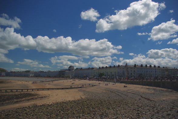 Upper half : Blue sky with white clouds.
Center: a row of buildings
Lower half; beach 