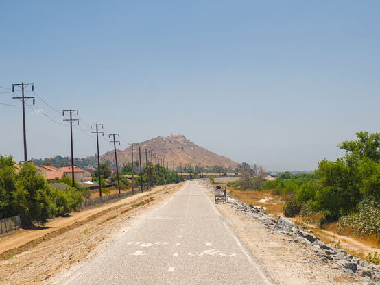 A concrete bike path leads into the distance towards a dry hill