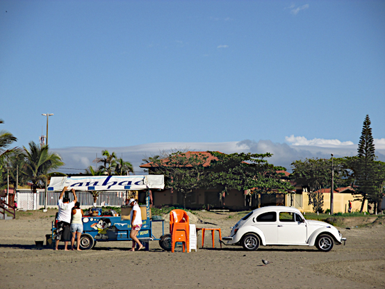 Foto van Volkswagen kever op strand bij een stalletje voor verkoop