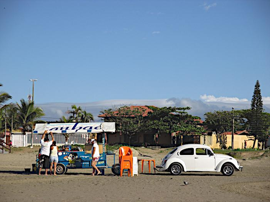Foto van Volkswagen kever op strand bij een stalletje voor verkoop