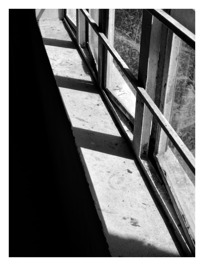 An angled view of a barred window, where strong sunlight casts sharp, dark shadows across the concrete sill. - Google Gemini 2.5 Pro