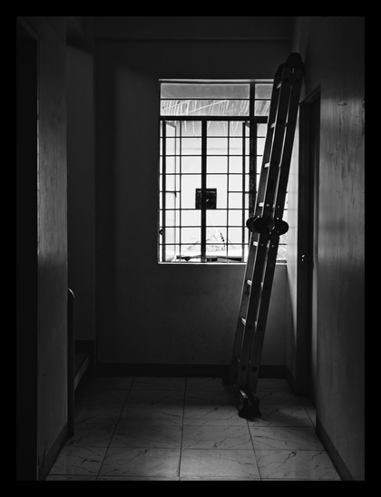 A dimly lit, narrow hallway with a tiled floor. A ladder is propped against a wall next to a barred window. - Google Gemini 2.5 Pro
