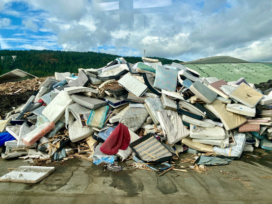 Pile of mattresses waiting to be disassembled and recycled.