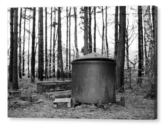 Black and white photograph of an iron charcoal maker amongst a clump of trees.  The image is shown printed upon a block canvas.