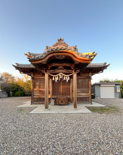 Un pequeño templo de madera con los típicos techos curvados. Está en una explanada con suelo de gravilla. No debe tener más de 2 o 3 metros de lado.