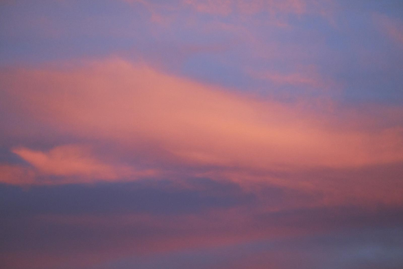 Soft sunset sky with broad streaks of peach-pink clouds layered over muted blue and violet tones, creating a gentle gradient across the frame.
