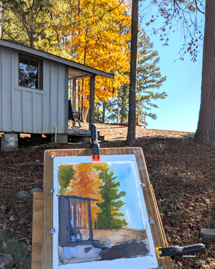 First shot painting a bright yellow orange tree hit by the late morning sun with a small building and rocking chair in the foreground.