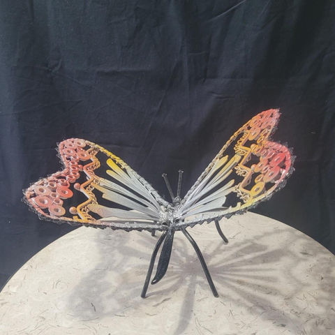 Bijou 
Un papillon en rebut d'acier et peints en jaune et rouge. Le contour est noir ainsi que ses pattes. 