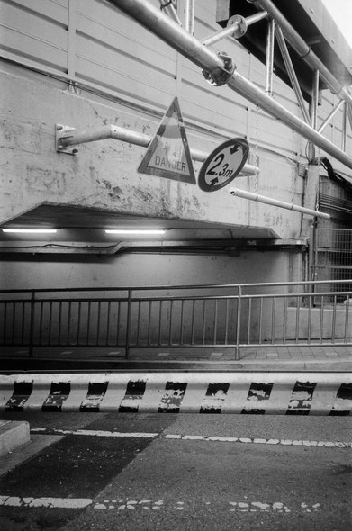 역곡역 굴다리를 도보에서 찍은 흑백사진. 낡은 굴다리 위로 '위험', '2.3m 높이제한' 표지판이 붙어있다. 아래쪽으로 중앙경계석과 도보에 설치된 안전 울타리가 보인다.