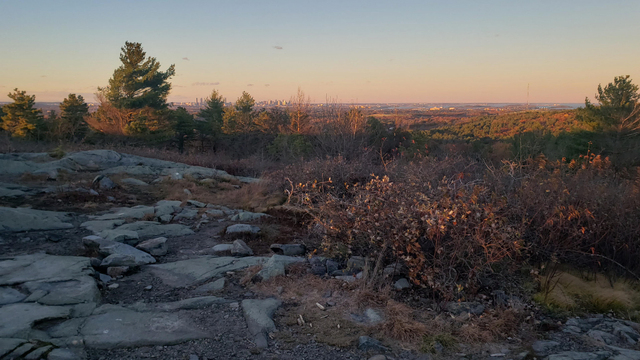 The Boston skyline and Boston harbor are visible in the late day sunlight as photographed from Buck Hill.