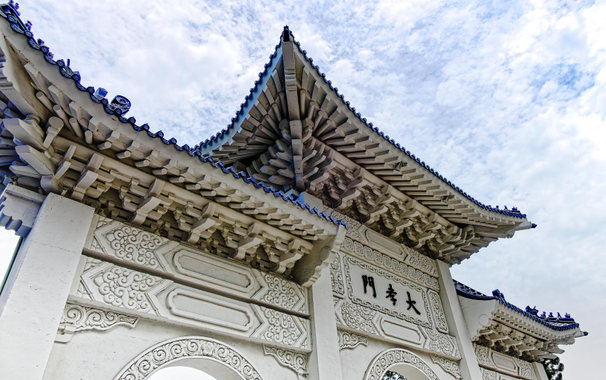 Frog’s-eye view of a large gate against a cloudy summer sky.