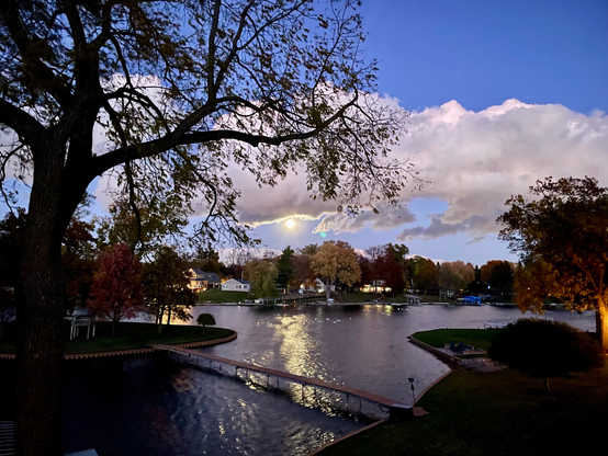 Photograph of a rising moon over a lake with clouds above.