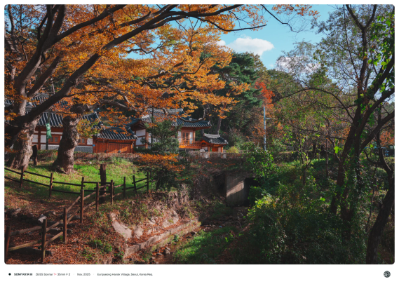 형형색색에 단풍이 든 나무, 볕이 드는 한옥, 그 아래를 지나가는 냇가.