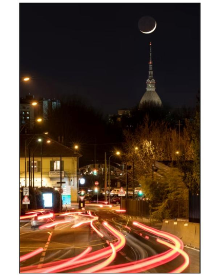 View of the moon on top of Mole Antonelliana and car lights.