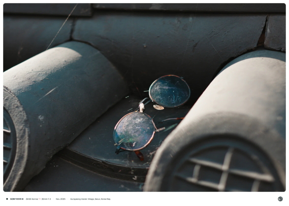 한옥 담장의 기와 위로 버려진 낡은 안경이 비스듬이 올려져 있는 모습.