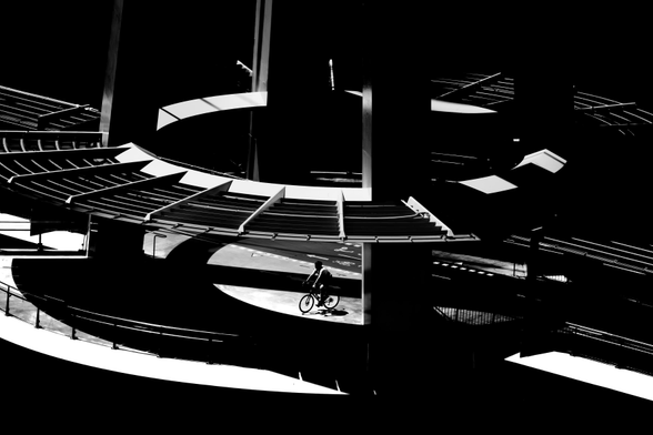 Black and white picture of a person on a bike on a a pedestrian bridge in brisbane.  It's high contrast black and white picture