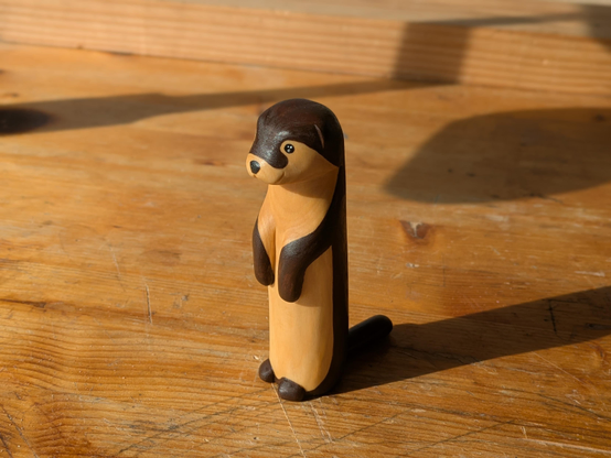Sculpture, woodcarved standing up otter on a workbench