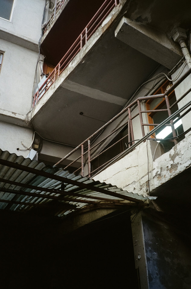 을지로의 어느 상가를 아래에서 올려다보며 찍은 사진. 낡은 콘크리트 구조물이 층층이 올라가있고 난간은 붉은 철제로 되어 있어 복도 안쪽 입구가 언뜻 보인다. 입구와 창문틀은 나무로 만들어졌다. 1층 입구쪽에는 비닐 슬레이트로 지붕을 만들었다.