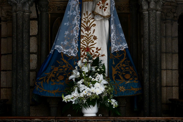 A bouquet of flowers at the feet of a statue