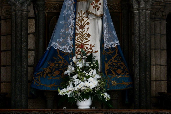 A bouquet of flowers at the feet of a statue
