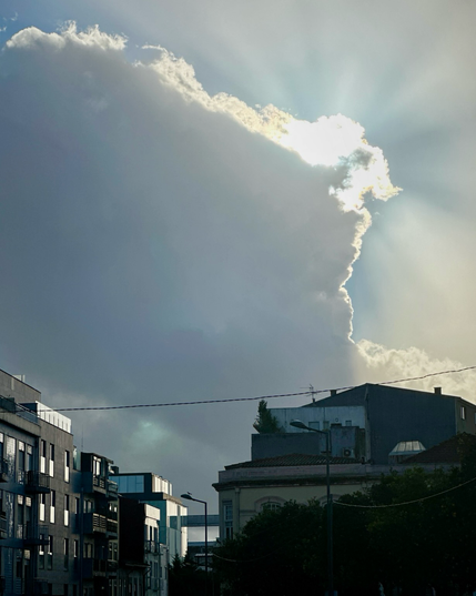 The sun peeking out from a large cumulus cloud in Braga Portugal 