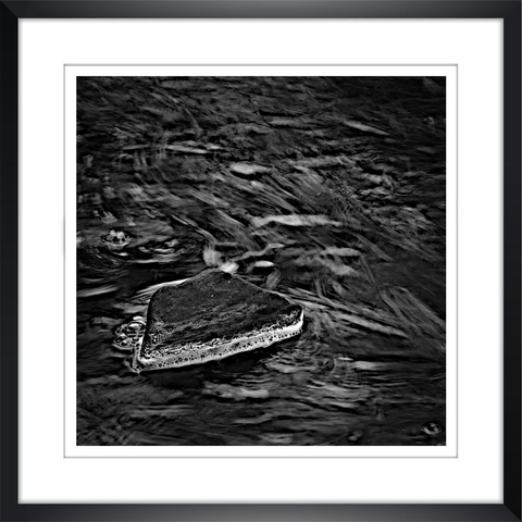 Un rocher dépasse des flots sombres d'une rivière. L'image est présentée dans un mince cadre noir avec passe-partout.
-
Ein Felsen ragt aus den dunklen Fluten eines Flusses heraus. Das Bild wird in einem schmalen schwarzen Rahmen mit Passepartout präsentiert.
-
A rock protrudes from the dark waters of a river. The image is presented in a thin black frame with a mat.