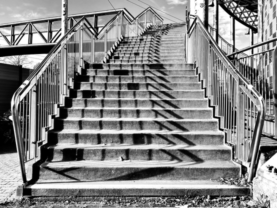 Treppenaufgang zur Fußgängerbrücke mit Schatten vom Geländer