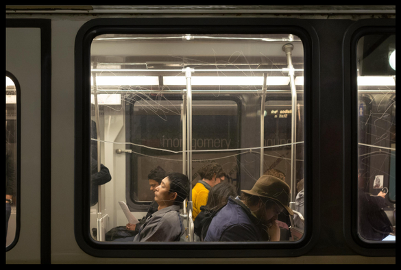 A view through the window of an outbound Muni streetcar as it pauses at an underground station during a Friday afternoon commute. The seated passengers look exhausted, head burrowed in phones or newspapers or, in one case, head tilted back with eyes closed. It feels like they had a long week.
