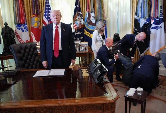 A photo captured this week where a man collapsed in an Oval Office meeting and the president stands away from the commotion, gazing away, clearly annoyed at the interruption. The photographer masterfully captures a sociopathic lack of empathy. A chair is overturned and a pair of legs are in the air. The remaining people are trying to help. Reportedly, RFK jr fled the room. 