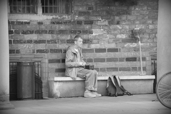 A homeless musician playing a self-made guitar - strings strung across the length of a common shovel - in Bremen. Copyright Urban Camera 2024