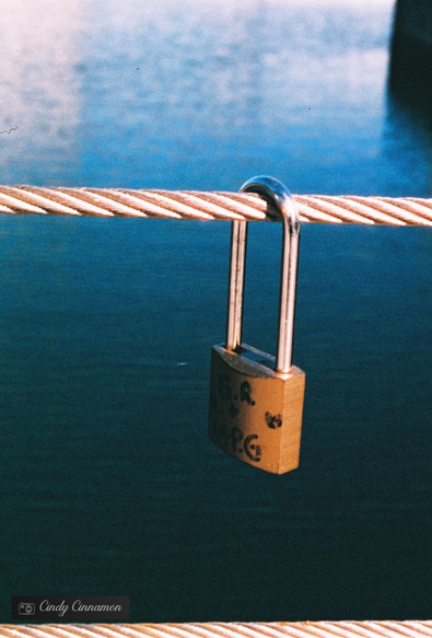 Cadenas sur un câble sur fond d’eau. Photographie par Cindy Cinnamon