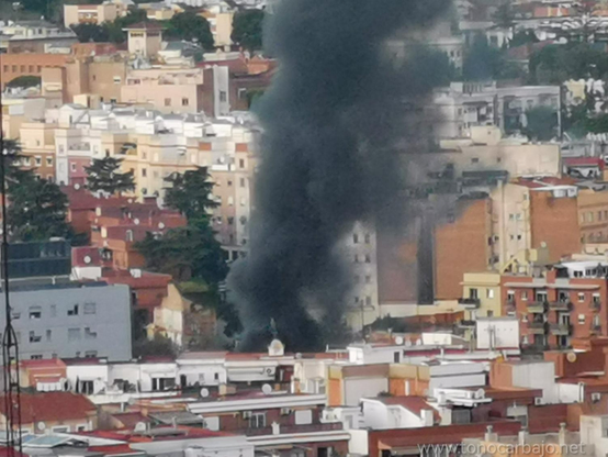 Se ve la ciudad con una columna de humo negro. Las montañas de la sierra de Collserola al fondo y el cielo . La foto es un primer plano