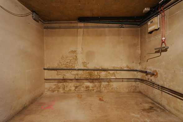 Photo d'une pièce située en sous-sol et dont les murs, sol et plafond sont couleurs béton