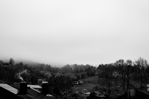 Black-and-white photograph of the Chiemgau Alps shrouded in fog.