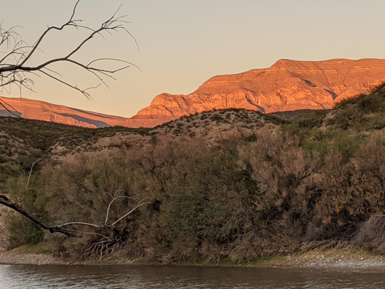 The last rays of sun shine a brilliant orange on the upper hills overlooking the Rio Grande 