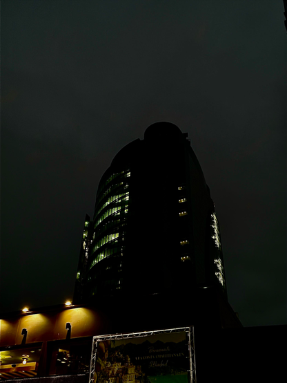 Torre iluminada de noche con un cielo de tonos azules y verdes, gris en esencia.