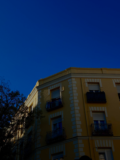 Fachada amarilla iluminada en la parte superior izquierda por el sol.