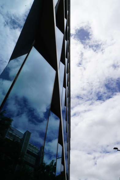 Picture of a glass skyscraper with reflection of the sky on the glasses, the sky is nicely blue