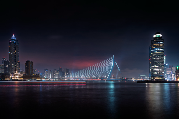 Een witte kabelbrug in de nacht. Links en rechts hoge torens met vele lampjes. 